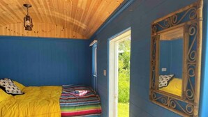 A room with a bed, a window, a mirror, and a sink. - Shepherds Hut in Dark Sky Reserve

 (Gwynfe)