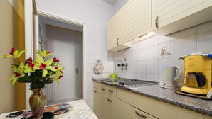 A kitchen with white cabinets, a granite countertop, a coffee maker, and a vase with flowers. - Pretty Apartment With Balcony (Porec)