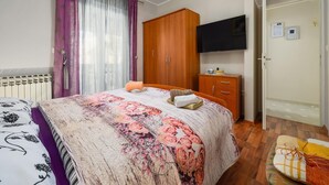 A bedroom with a bed, a wardrobe, a television, and a radiator. - Pretty Apartment With Balcony (Porec)