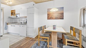 A modern kitchen with white cabinets, a wooden countertop, and a dining area with a table and chairs. - 2 bedroom stunning home in Fanø (Fanø)