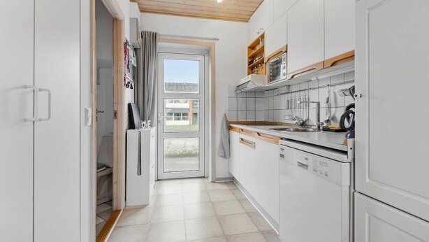 A modern kitchen with white cabinets, a wooden countertop, and a built-in oven. - 2 bedroom stunning home in Fanø (Fanø)