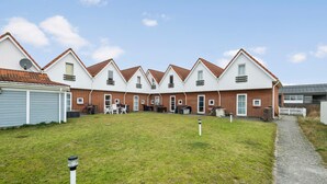A row of white houses with red roofs, a grassy yard, and a gravel path. - 2 bedroom stunning home in Fanø (Fanø)