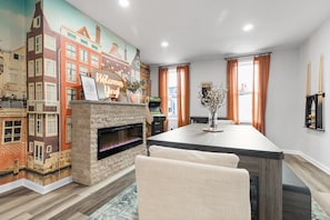 A modern living room with a fireplace, a cityscape mural, and a pool table. - Game Room: Pool Table, Ping Pong + Arcade · 2 Kings · Fenced Yard · Parking (Pittsburgh)
