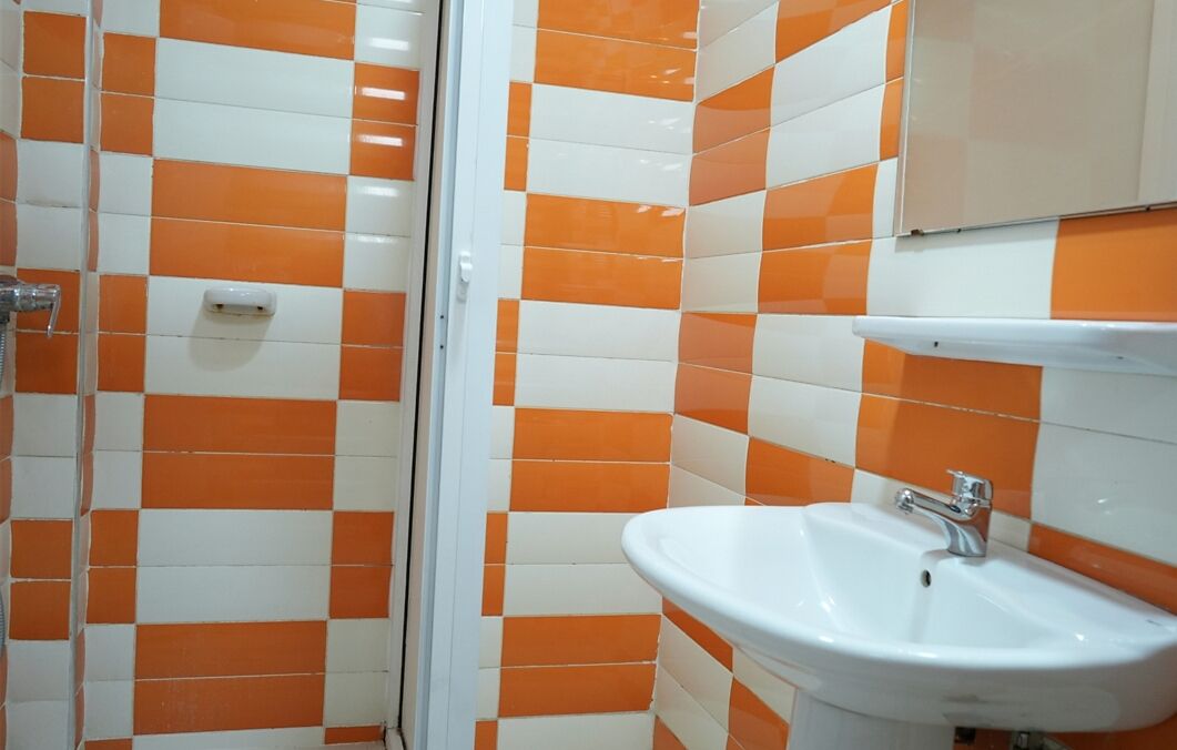 A bathroom with orange and white checkered tiles, a white sink, and a mirror above it.