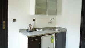 A compact kitchen with a granite countertop, a stainless steel sink, a kettle, and a small refrigerator. - Coqueto apartment ghiliz (Marrakech)