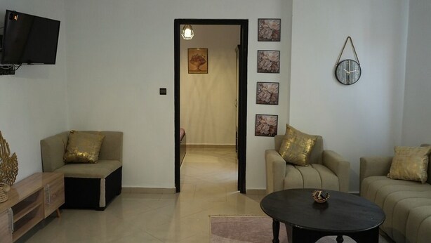 A living room with two sofas, a coffee table, a TV, and a wall clock. - Coqueto apartment ghiliz (Marrakech)
