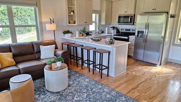 A modern kitchen with a central island, bar stools, and a refrigerator. - Cozy Cabin by the Lake (Tyler)