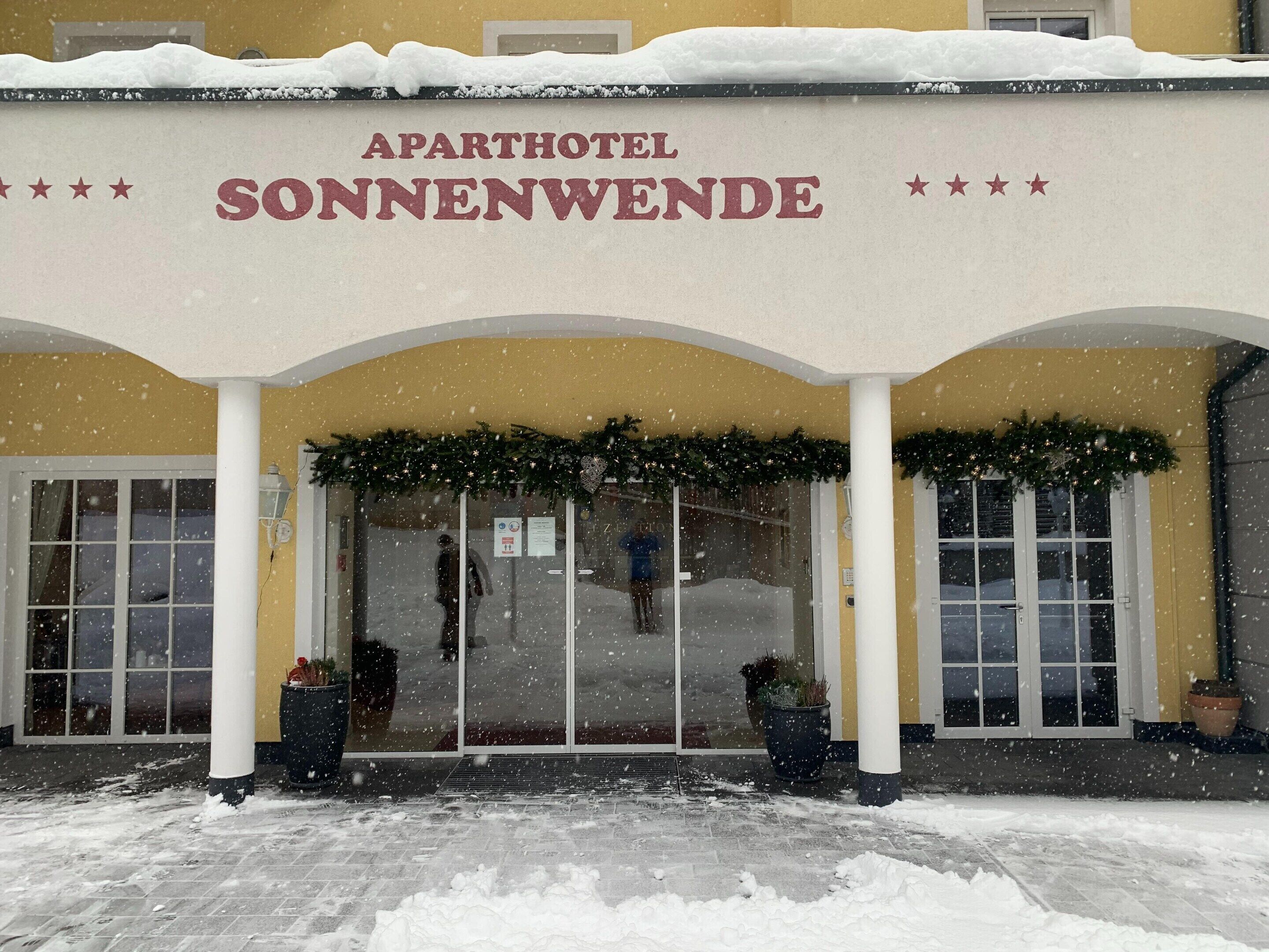 The entrance of the Aparthotel Sonnenwende with a snow-covered roof and garlands.