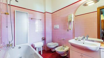 A bathroom with a bathtub, toilet, bidet, and sink.