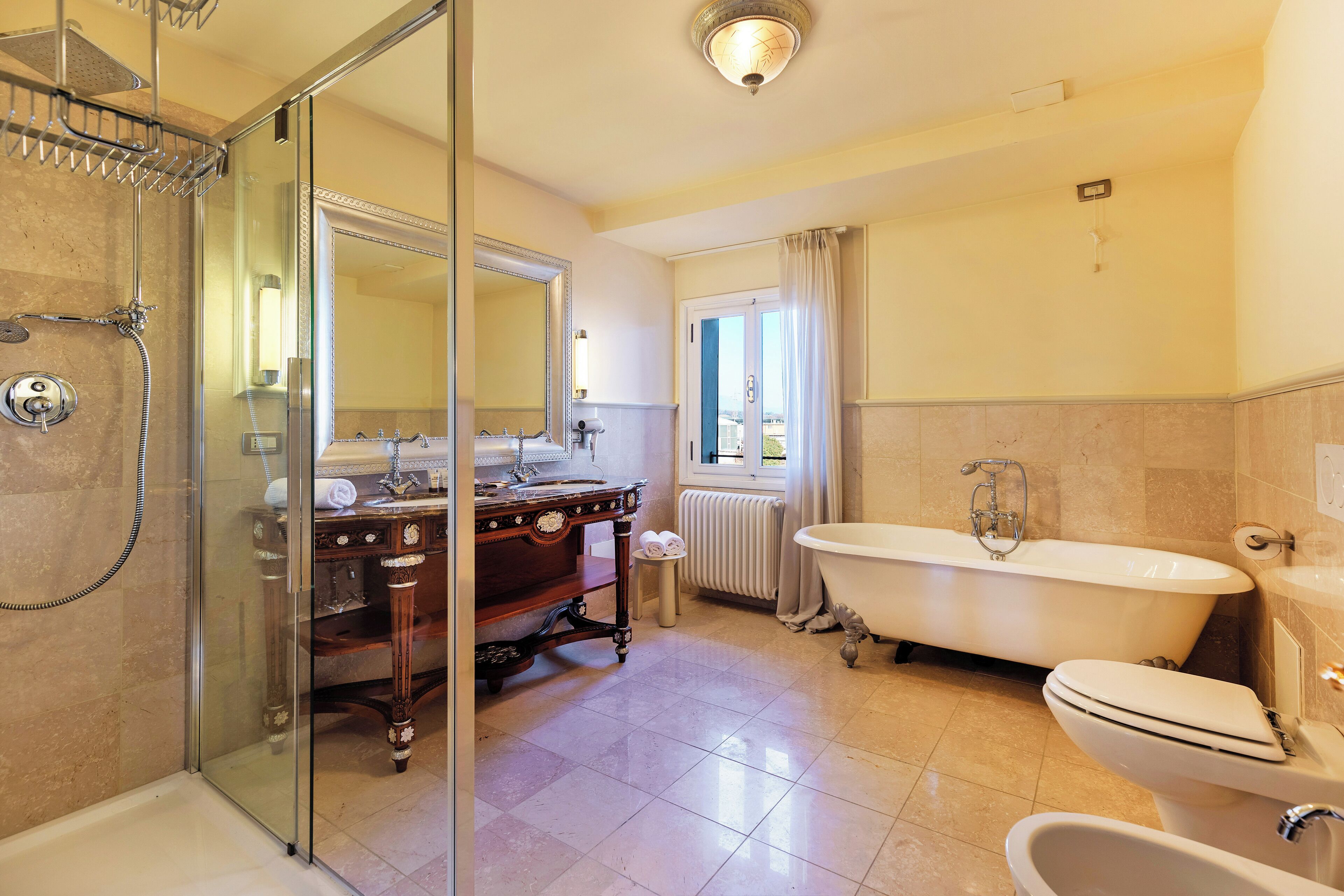 A bathroom with a glass-enclosed shower, a freestanding bathtub, a vanity with a mirror, and a toilet.