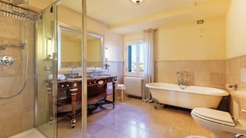 A bathroom with a glass-enclosed shower, a freestanding bathtub, a vanity with a mirror, and a toilet.