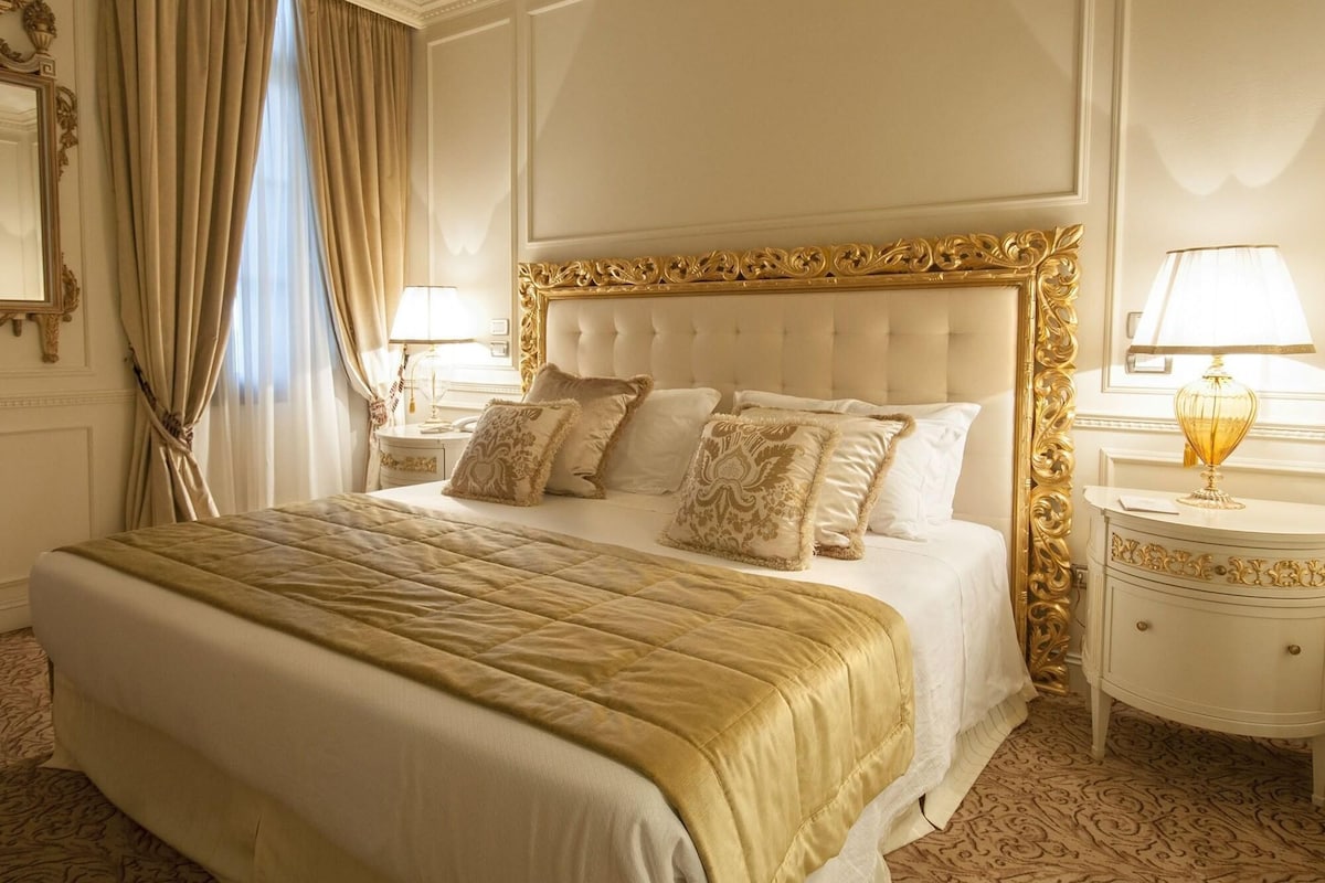 Une chambre d’hôtel luxueuse, dotée d’un grand lit, d’une tête de lit décorée et de deux tables de chevet assorties.