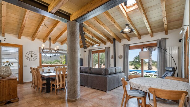A spacious living area with a wooden ceiling, a large sofa, a dining table with chairs, and a view of the outdoors. - 4 bedroom villa with private pool and barbecue (Inca)