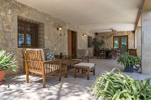 A stone-walled patio with wooden furniture, including a table and chairs, and potted plants.