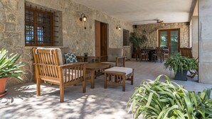 A stone-walled patio with wooden furniture, including a table and chairs, and potted plants. - 4 bedroom villa with private pool and barbecue (Inca)