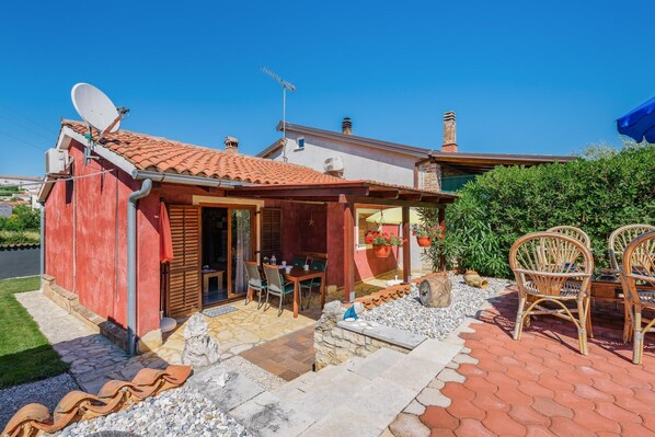 A small house with a tiled roof, a satellite dish, and a patio with outdoor furniture. - Nice Apartment With Pool (Visnjan)