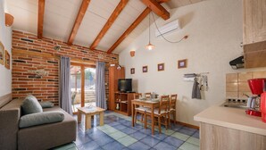 A cozy living room with a sofa, a dining table, and a TV. - Nice Apartment With Pool (Visnjan)