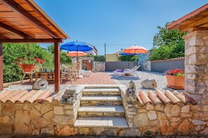 A stone staircase leading to a covered patio area with outdoor furniture and umbrellas. - Nice Apartment With Pool (Visnjan)
