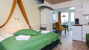 A bedroom with a large bed, a desk, a chair, and a kitchenette. - 2 Person Holiday Park Home in Romo (Rømø)
