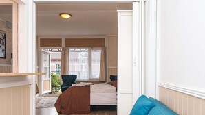 A cozy room with a bed, a blue sofa, and a window with curtains. - 2 Person Holiday Park Home in Romo (Rømø)