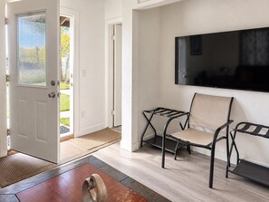 A modern living room with a flat-screen TV mounted on the wall, a pair of chairs, and a wooden coffee table.