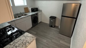A compact kitchen with a stove, microwave, washing machine, and refrigerator.