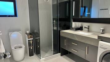 A modern bathroom with a toilet, bidet, and a washing machine.