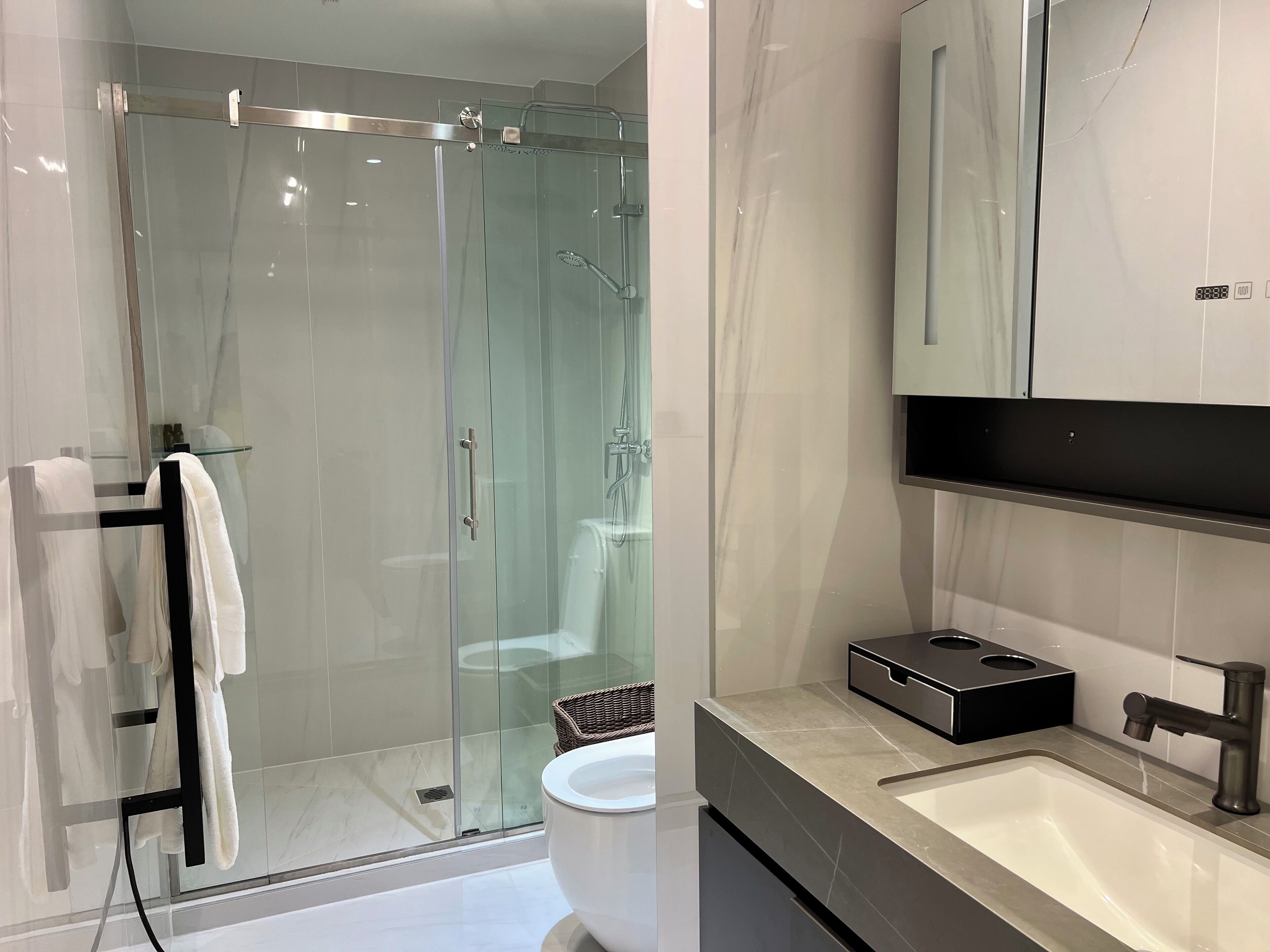 A modern bathroom with a glass-enclosed shower, a white sink, and a black vanity.