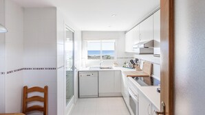A compact kitchen with a view of the beach, white cabinetry, and a wooden chair. - Nice apartment in Campello with WiFi (Campello)