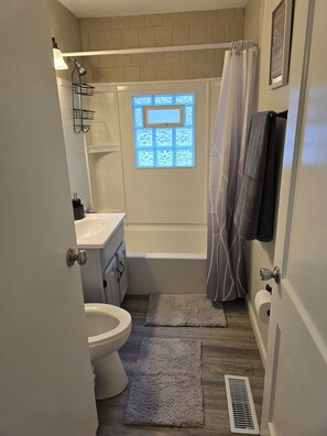 Een badkamer met een bad, toilet, wastafel en een raam met decoratief ontwerp.