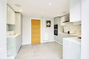 A modern kitchen with white cabinetry, a wooden door, and a central island.