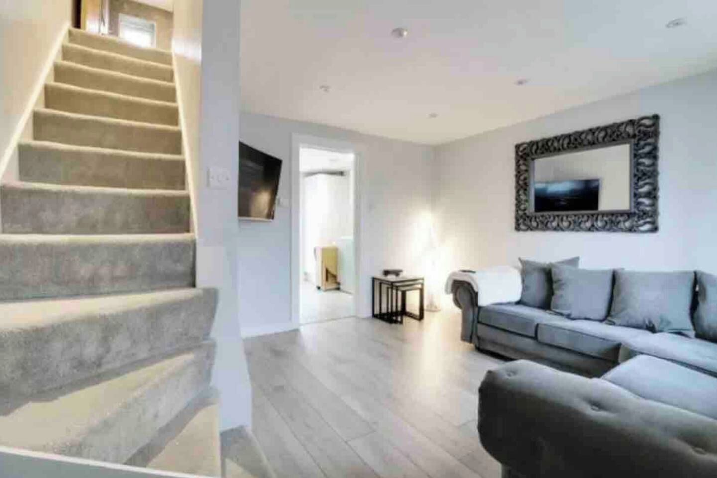 A staircase leading to a landing, a grey sofa, and a framed mirror on the wall.