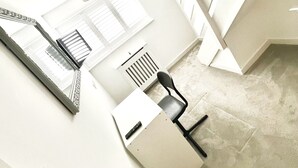 Une pièce moderne et minimaliste, dotée d’une grande fenêtre, d’un luminaire au plafond, d’une chaise et d’un bureau.