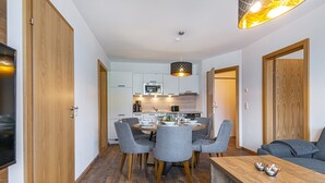 Eine moderne Küche mit weißen Schränken, einer Mikrowelle und einem Essbereich mit einem runden Tisch und vier Stühlen.
