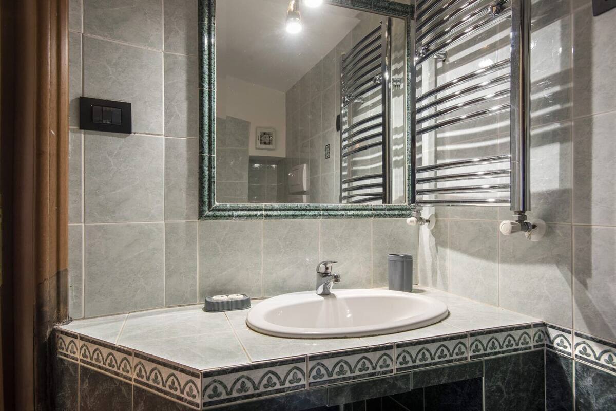 A bathroom with a white sink, a mirror, and a towel rack.