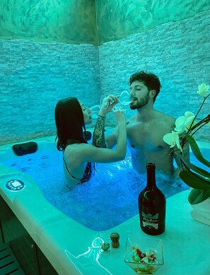 A couple in a hot tub with a bottle of wine and flowers on the side. - The Life Hotel (Marcellina)