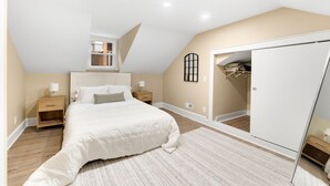 Un dormitorio con una cama grande, un armario, una mesita de noche y un espejo.