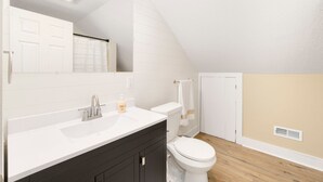 Un baño moderno con un tocador blanco, un lavabo, un inodoro y un espejo.