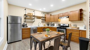 Una cocina moderna con armarios de madera, un refrigerador de acero inoxidable y una mesa de comedor con sillas.