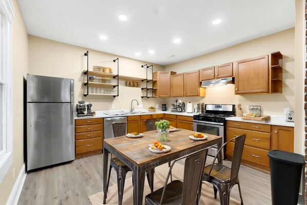 A modern kitchen with wooden cabinets, a stainless steel refrigerator, and a dining table with chairs. - Trendy 2-bedroom house in downtown Fort Wayne (Fort Wayne)