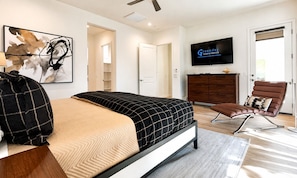 Una camera da letto moderna con un letto, una televisione, un armadio e un angolo salotto.