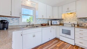 A modern kitchen with white cabinets, a microwave, an oven, and a toaster. - 4-bedroom house in welcoming Rodanthe with AC, WiFi. Enjoy your stay (Rodanthe)
