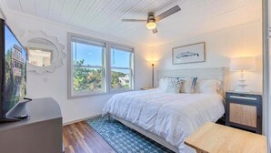 A bedroom with a bed, a ceiling fan, a TV, and a window. - 4-bedroom house in welcoming Rodanthe with AC, WiFi. Enjoy your stay (Rodanthe)