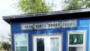 Una casa blu con veranda, due porte e tre finestre.