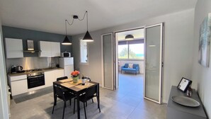 A modern kitchen with a dining area, a sofa, and a view of the outdoors. - Piante Del Principe Apartments and Rooms (Carini)