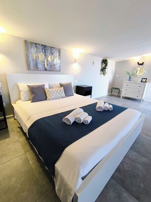 A modern bedroom with a large bed, a nightstand, a dresser, and a wall-mounted mirror. - Piante Del Principe Apartments and Rooms (Carini)