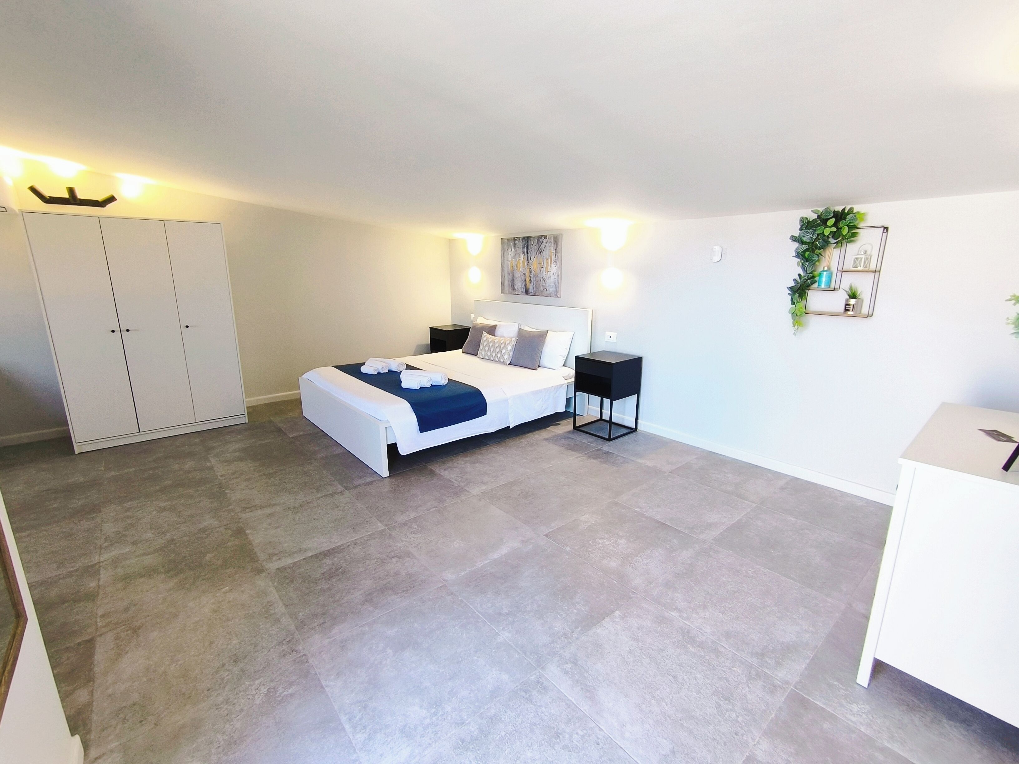A bedroom with a bed, bedside tables, a wardrobe, and a desk.