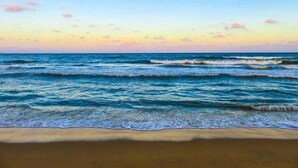 A beach with waves and a clear sky.