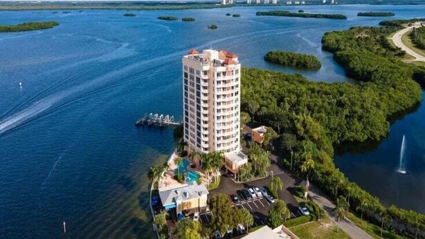 A high-rise hotel with a pool, surrounded by water and greenery.