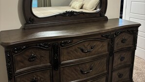 A dark wooden dresser with a large mirror and multiple drawers.